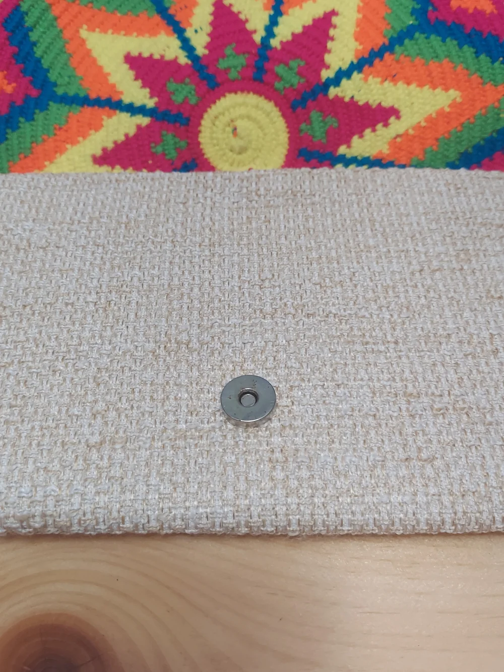 Handmade Wayuu-style jute clutch featuring a vibrant, multicolored beaded floral